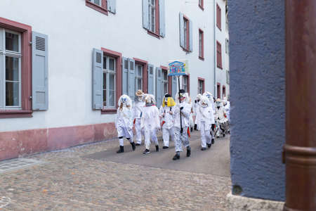 Basel carnival. Nadelberg, Basel, Switzerland - February 21st, 2018. Carnival group in white costumes in the old townのeditorial素材