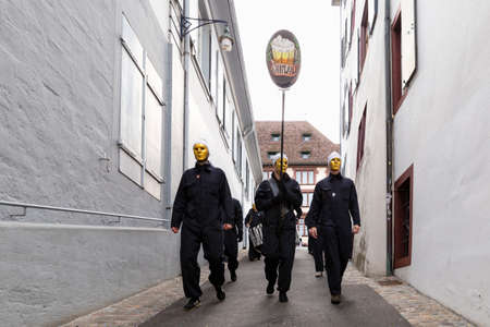Archivgaesslein, Basel, Switzerland - March 12th, 2019. Front view of a marching carnival group in black costumesのeditorial素材