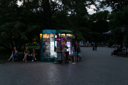 Ukraine, Odessa, Deribasivska Street, 11th of June 2019. A small illuminated newspaper kiosk in the city garden at sunset.のeditorial素材