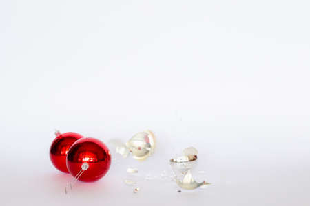 Broken red and silver Christmas baubles lying on white backgroundの写真素材