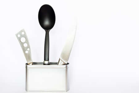 Assortment of kitchenware and cooking tools in a square silver colored metal box with copy space on white backgroundの写真素材