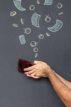 Concept of earning money with a brown leather wallet held in two hands in front of a blackboard with...
