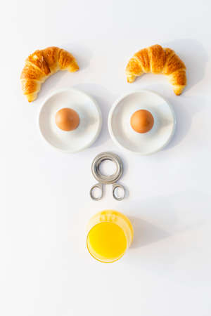 Fun breakfast concept with abstract astonished human face made of breakfast items on white...