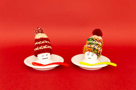 Fun breakfast concept with boiled eggs with abstract happy and annoyed human faces wearing knitted...