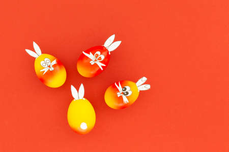 Colorful painted easter eggs with funny bunny ears and cartoon faces on red background