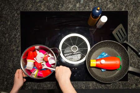Concept of food pollution with plastic waste. Top view of a persons hands at a stove with a frying...