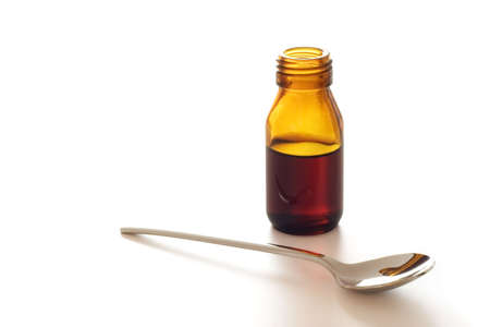 Bottle of cough syrup with a spoon isolated over a white backgroundの写真素材