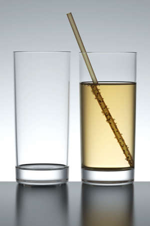 Full and empty soda glass isolated over a gray backlit background.の写真素材