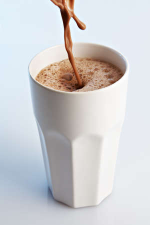 Chocolate drink pouring into a white ceramic glass.の写真素材