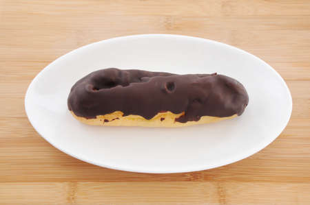 chocolate eclair cream puff on plate on table
