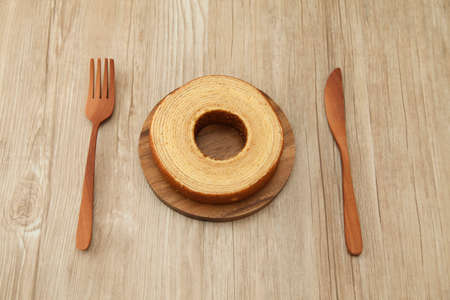 baumkuchen German doughnut cake on wood plate fork knife on table