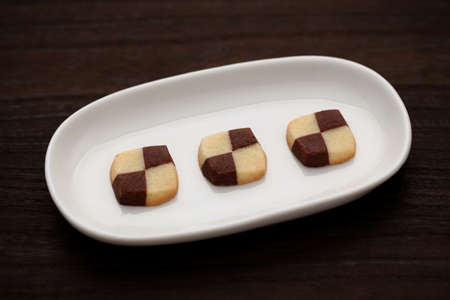 butter milk chocolate cookies biscuits isolated on plate on wood tableの写真素材