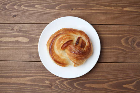 round danish bread on plate isolated on wooden tableの写真素材