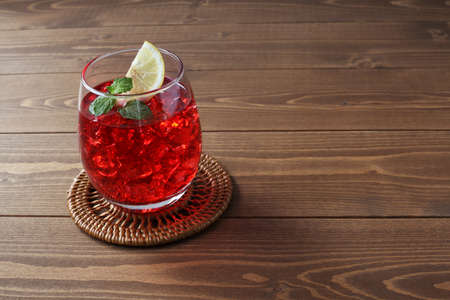 glass of cold tea red drink isolated on wooden tableの写真素材