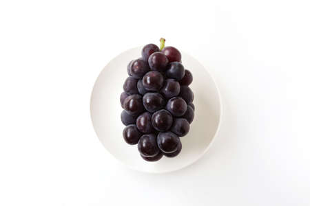 fresh bunch of grapes on plate isolated on white backgroundの写真素材