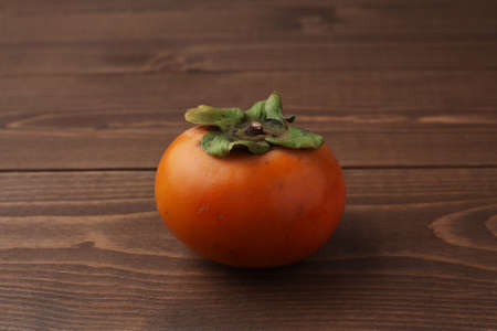 ripe persimmon closeup isolated on wood tableの写真素材
