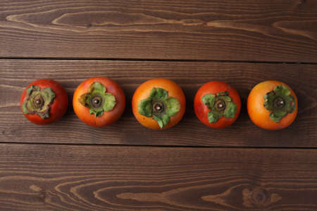 ripe persimmon closeup isolated on wood tableの写真素材