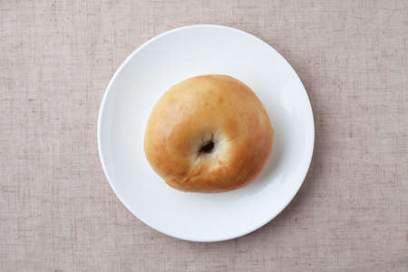 plain bagel bread on plate closeup isolated on table clothの写真素材