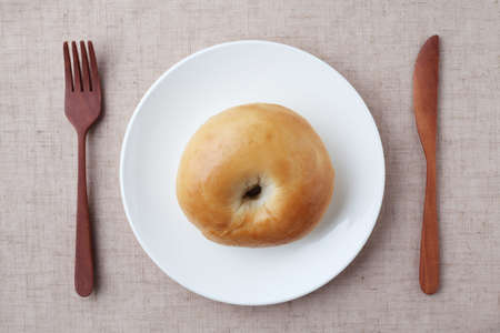plain bagel bread on plate closeup isolated on table clothの写真素材