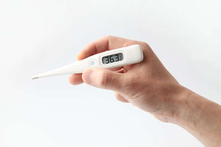 medical thermometer held in a male hand on white background