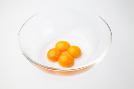 4 egg yolks in glass bowl isolated on white backgroundの写真素材