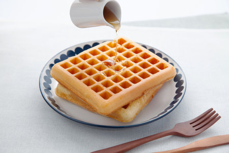 waffles pancakes with maple syrup on plate on tableの写真素材