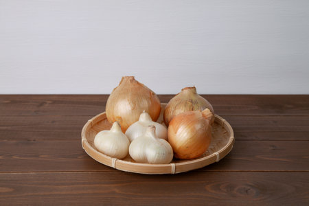 raw garlic onions isolated on wooden tableの写真素材
