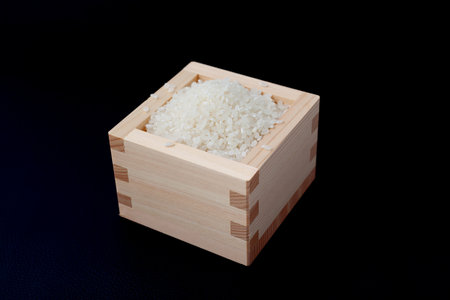 Japanese raw rice in wodden box isolated on black backgroundの写真素材