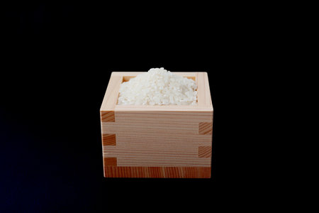 Japanese raw rice in wodden box isolated on black backgroundの写真素材