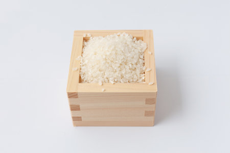 Japanese raw rice in wodden box isolated on white backgroundの写真素材