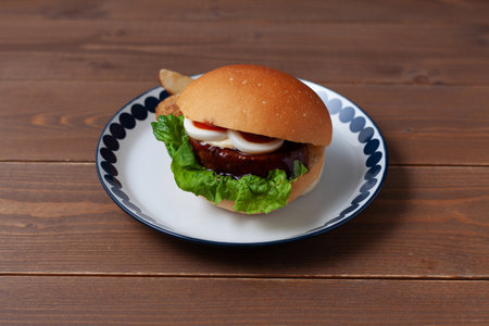 teriyaki hamburger with boiled egg on plate isolated on wooden tableの写真素材