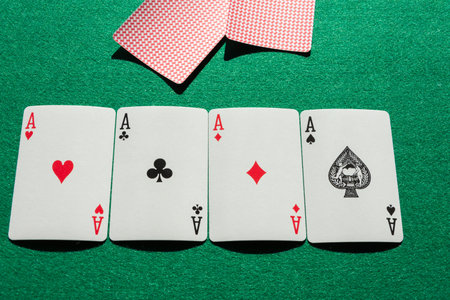 Top view of aces of poker deck, lined up, with covered cards, on green mat, horizontal