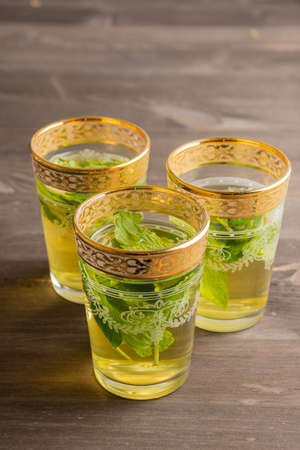 Top view of three glasses with tea and mint on dark wooden table, vertical, with copy spaceの写真素材