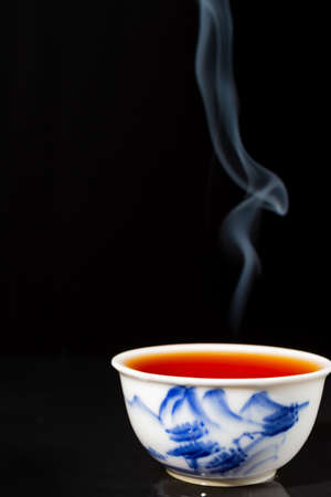 Close-up of steaming blue and white china tea cup, black background, vertical, with copy spaceの写真素材