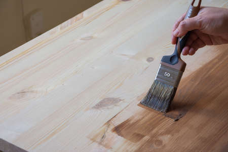 View of woman's hand with brush, varnishing a pine board, horizontalの写真素材