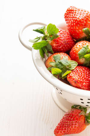 Close-up of strawberries in a white colander, on white wooden table, vertically, with copy spaceの写真素材