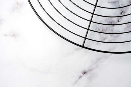 Aerial view of round black rack to cool desserts on white marble table, horizontalの写真素材