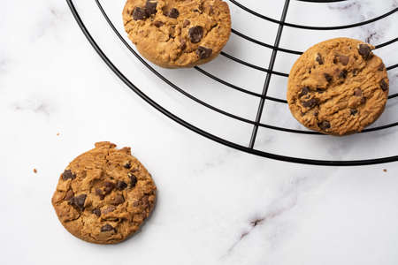Aerial view of chocolate cookies on black grid, on white marble table, selective focus, horizontal, with copy spaceの写真素材