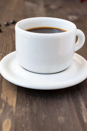 Close-up of white coffee cup with saucer on dark wooden table, vertical, with copy spaceの写真素材