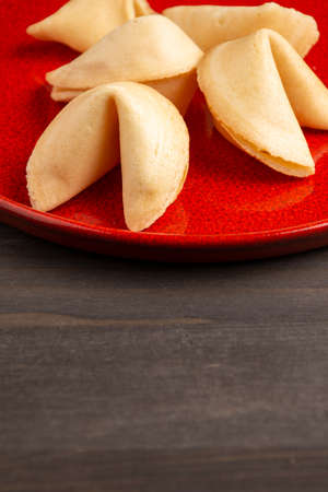 Top view of fortune cookies on red plate, on dark wooden table, in vertical, with copy spaceの写真素材