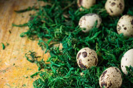 Top view of quail eggs on green grass and rustic wooden table, horizontal, with copy space