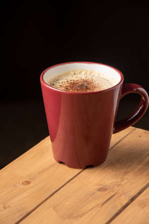 Top view of cup of cappuccino coffee on wooden table, dark background, vertical, with copy spaceの写真素材
