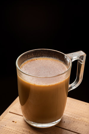 Aerial view of glass cup of coffee with milk, on wooden table, black background, vertical, with copy spaceの写真素材