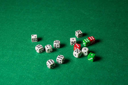 Wide shot of white, green and red dice on green playing mat, selective focus, horizontal, with copy spaceの写真素材