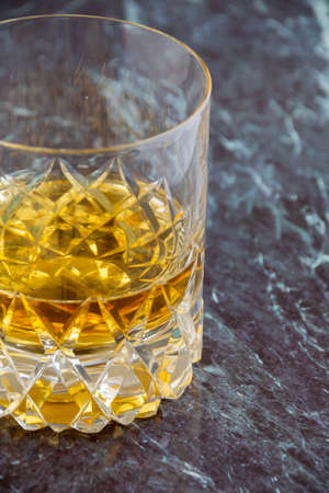 Top view of glass with whiskey on blue marble, vertical, with copy space