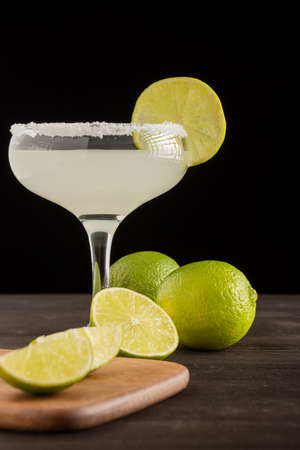 Close-up of limes and lemons and margarita cocktail, selective focus, black background, verticalの写真素材