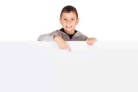 Advertising - Little kid standing behind a blank banner pointing to an advertisement isolated on whiteの写真素材