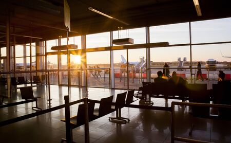 Silhouette of airline passengers in an Eindhoven airport lounge by sunsetのeditorial素材