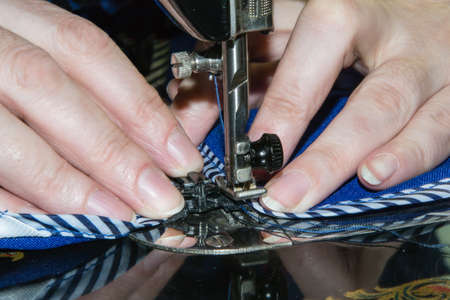Hands of the seamstress behind work on the sewing machineの写真素材