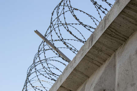 Concrete fence with a barbed wire against the skyの写真素材